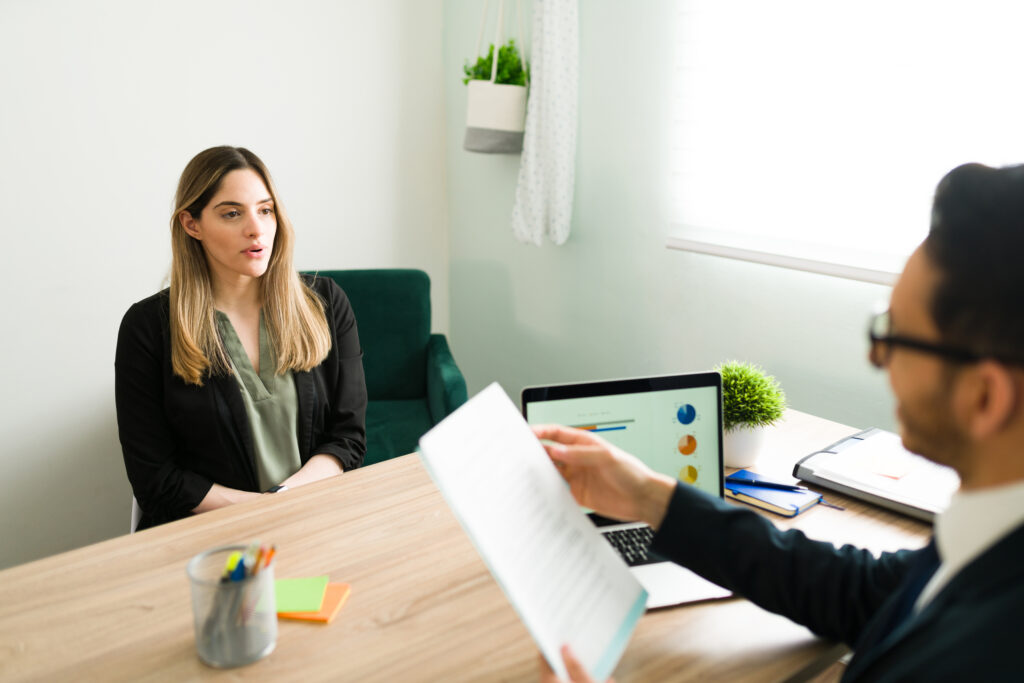 A young job applicant being interviewed by a hiring manager in a minimalist office setting.
