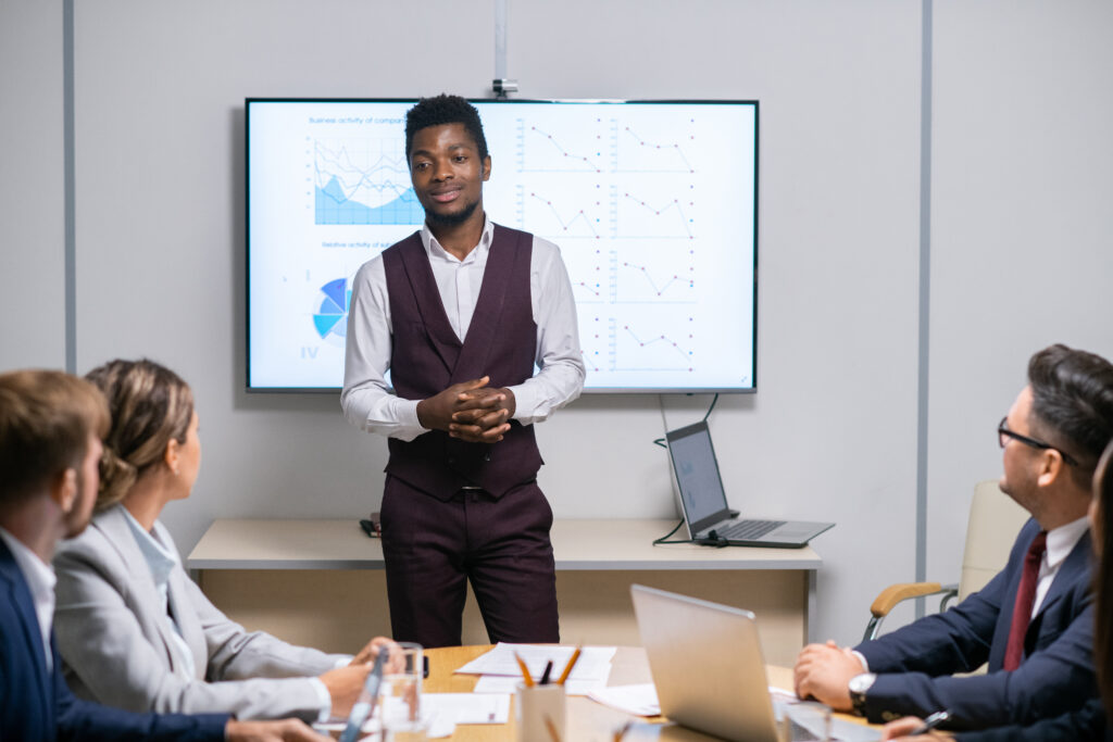 A young professional presenting in front of his colleagues in an office boardroom setting